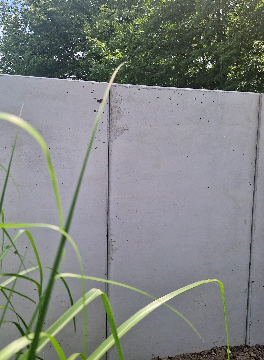 Gotowy mur ogrodzeniowy z prefabrykowanych płyt betonowych w otoczeniu zieleni