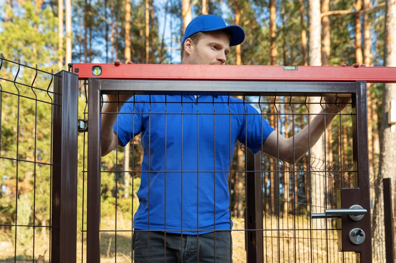 Monter sprawdza poziom furtki w ogrodzeniu panelowym